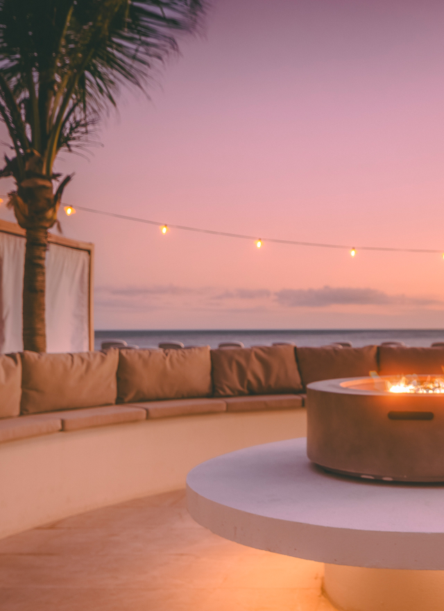 an outdoor patio with cozy seating and a firepit with ocean views